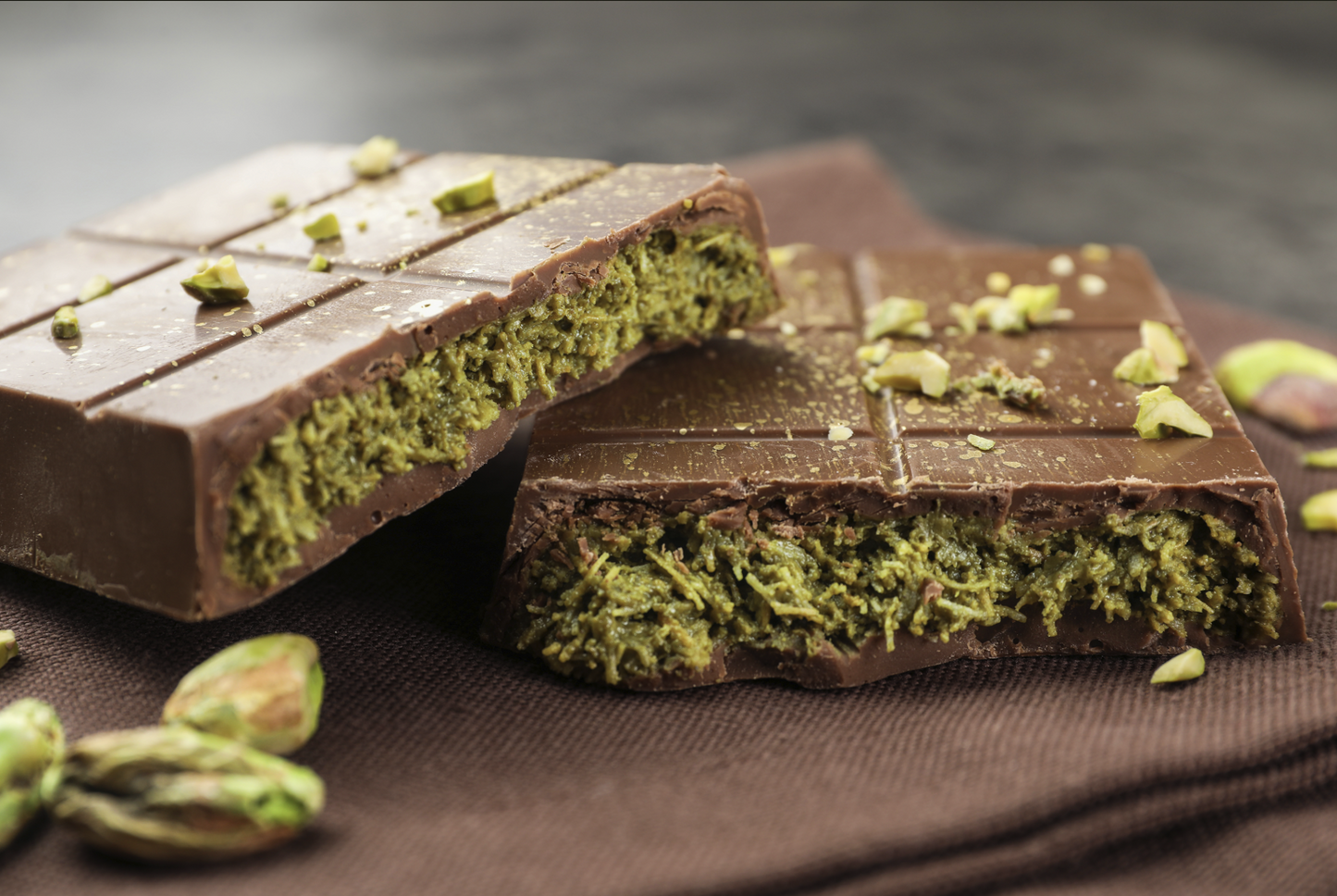 Dubai Chocolate bar with green filling and pistachios on a brown surface