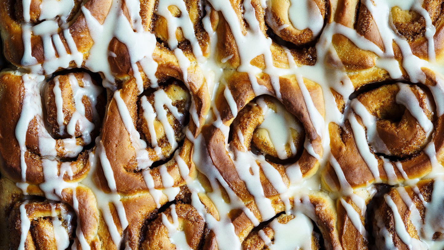 Close-up of cinnamon rolls with white icing drizzle