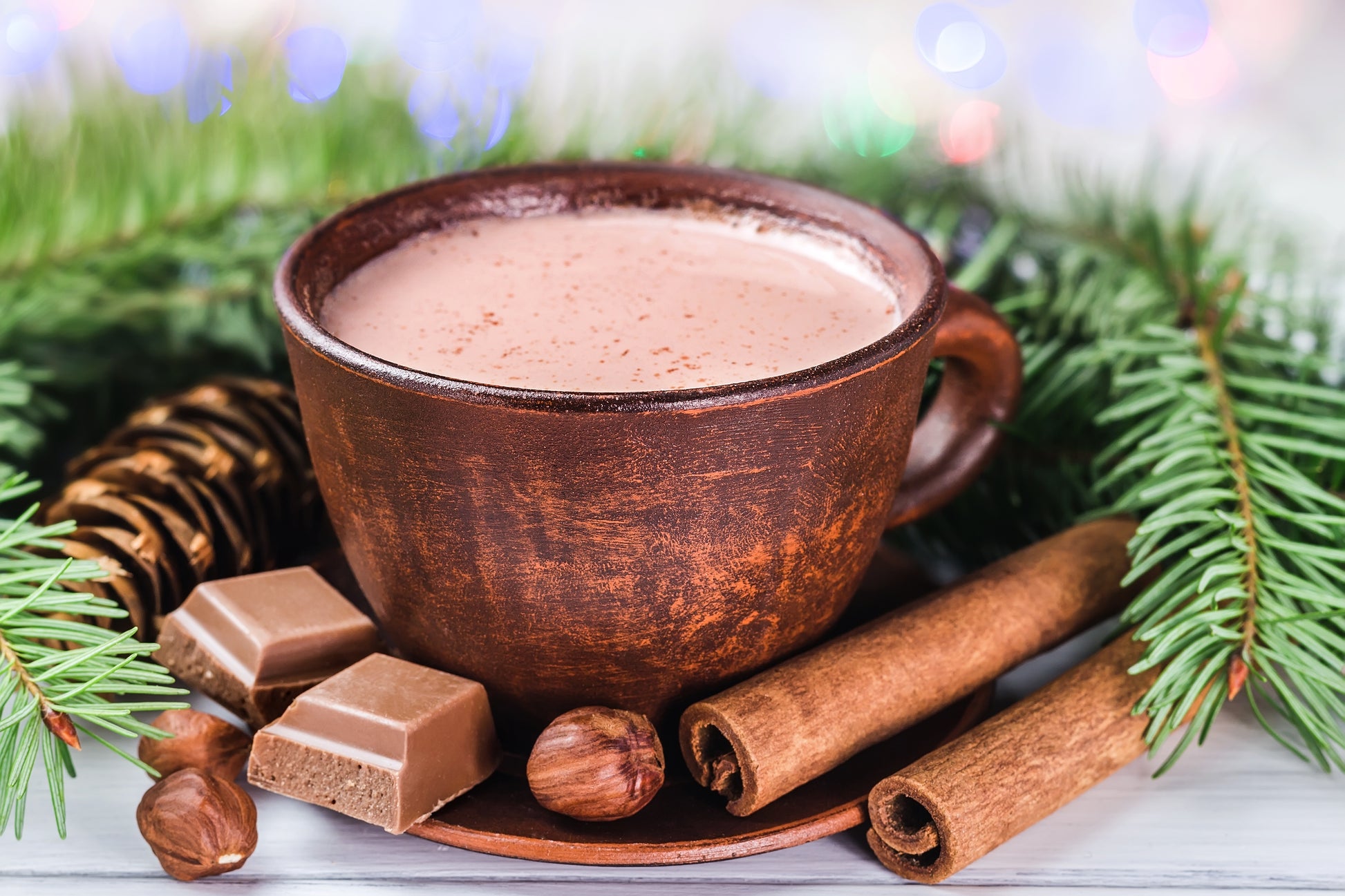 Hot chocolate in a wooden mug with festive decorations on a blurred background