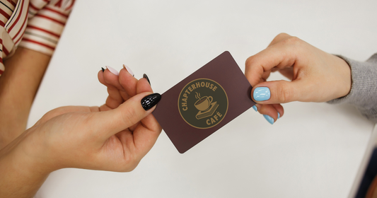two female hands passing a burgundy chapterhouse gift card as a gift